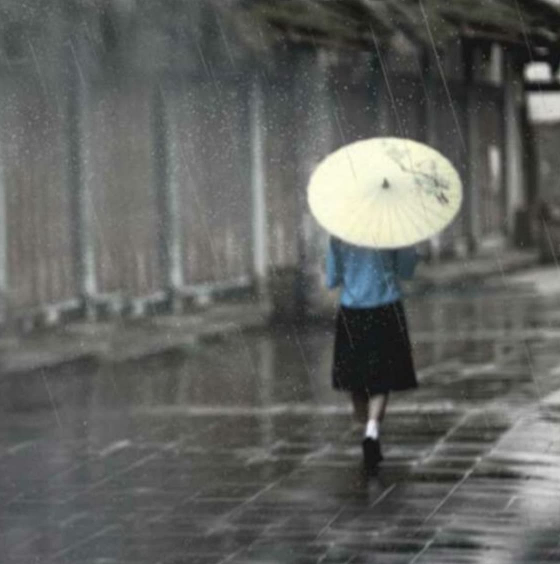 雨中撑伞走过姑苏古巷的行人